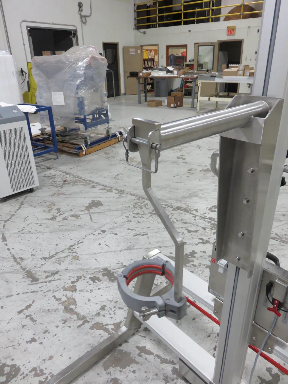 The clamp hanging from the lift bar, with the lift point above the bottle's center of mass