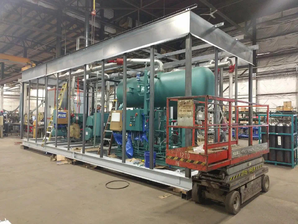 The enclosure's post frame going up around the refrigeration skid in the shop