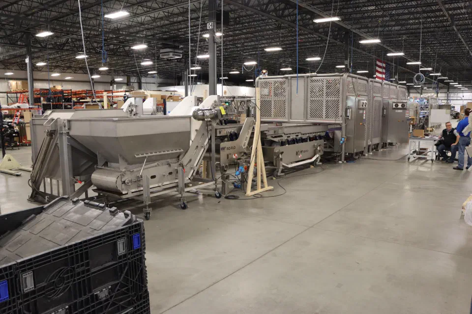 The primary system in the shop: product hopper and incline conveyor feeding vibratory pans ahead of the robot cells