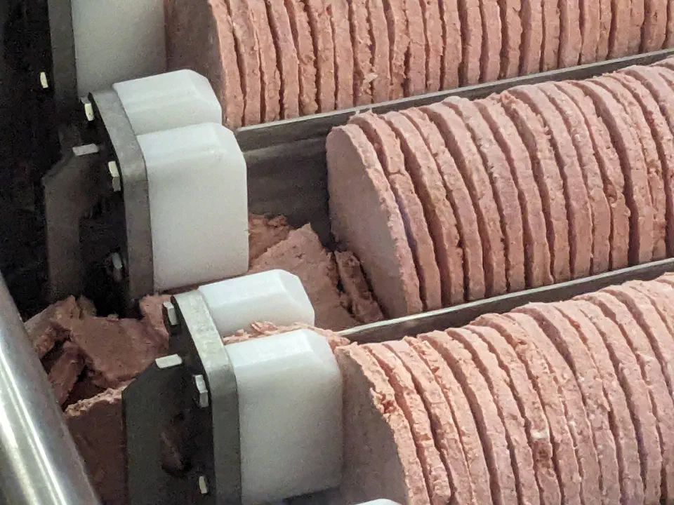 Frozen patties standing on edge against the stops on the vibratory pan