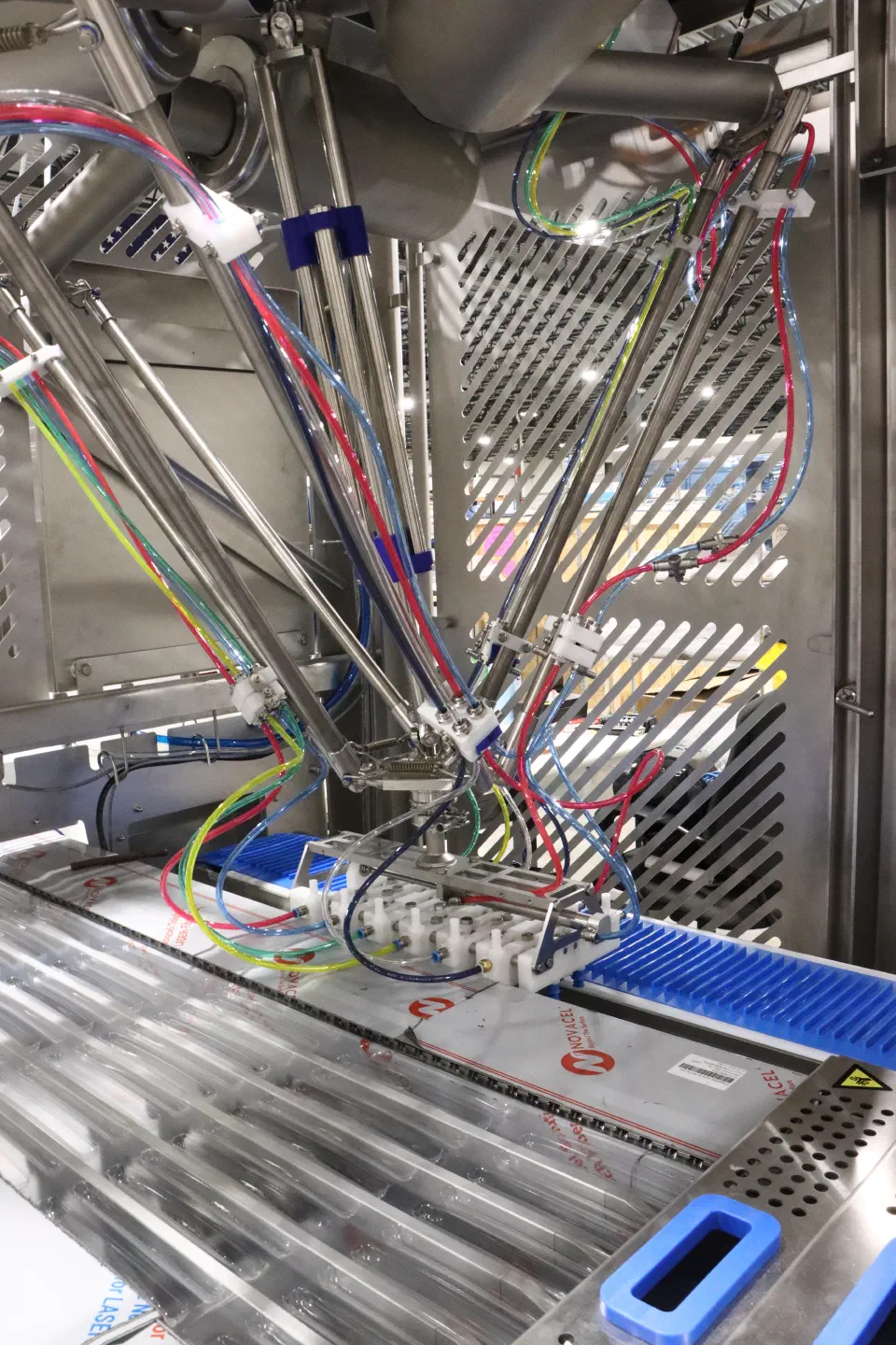 The delta robot above the collation conveyor, where the bowl feeder's chute feeds sticks in